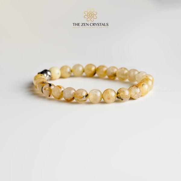 golden rutile bracelet with a silver clasp on a light gray background, branded 'The Zen Crystals'.
