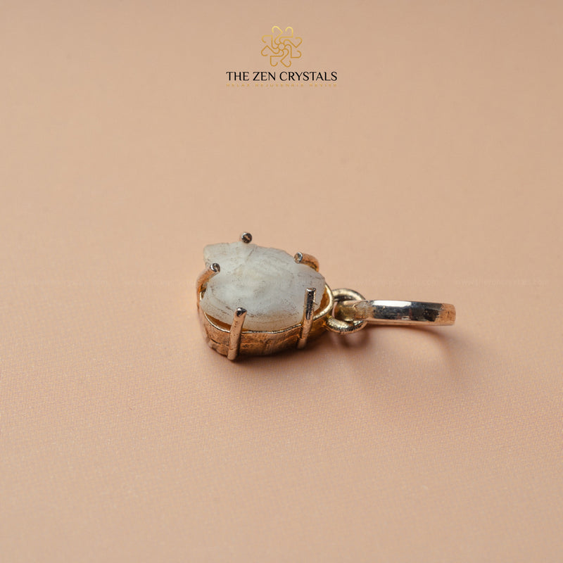 machh mani pendant with gold setting on a beige background, branded 'The Zen Crystals'.