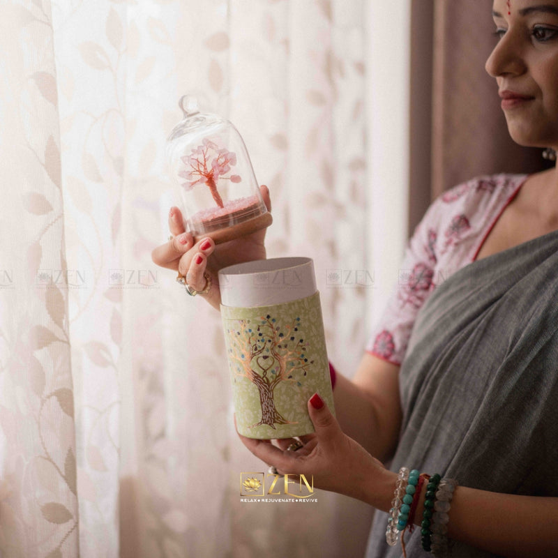 Woman holding a decorative glass bottle with a tree design against a light curtain background