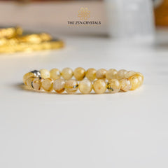 golden rutile bracelet on a white surface with 'The Zen Crystals' branding.