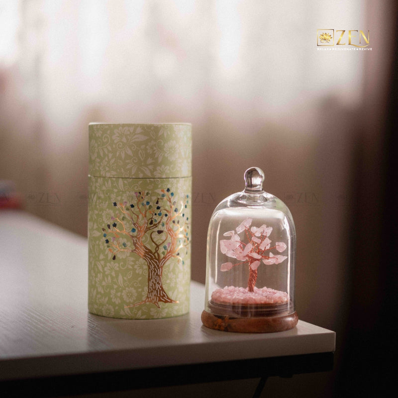 Decorative tree inside a glass dome and cylindrical container with tree design on a blurred background