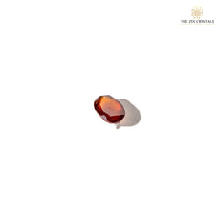 Faceted hessonite stone on a white background with 'The Zen Crystals' logo.