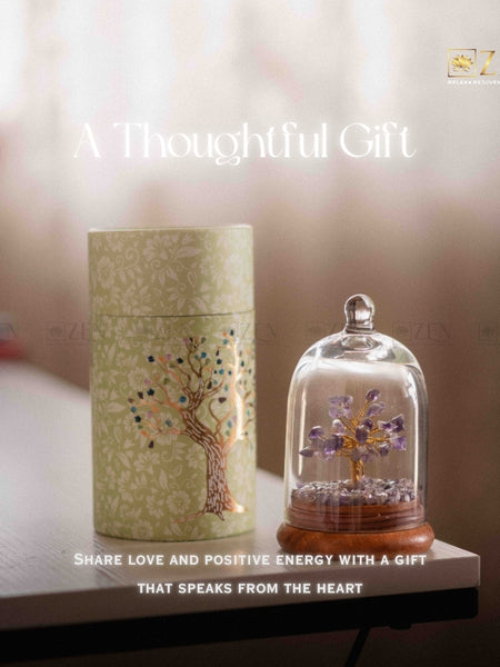 Decorative gift set with a cylindrical box and a glass dome containing a tree sculpture on a blurred background.