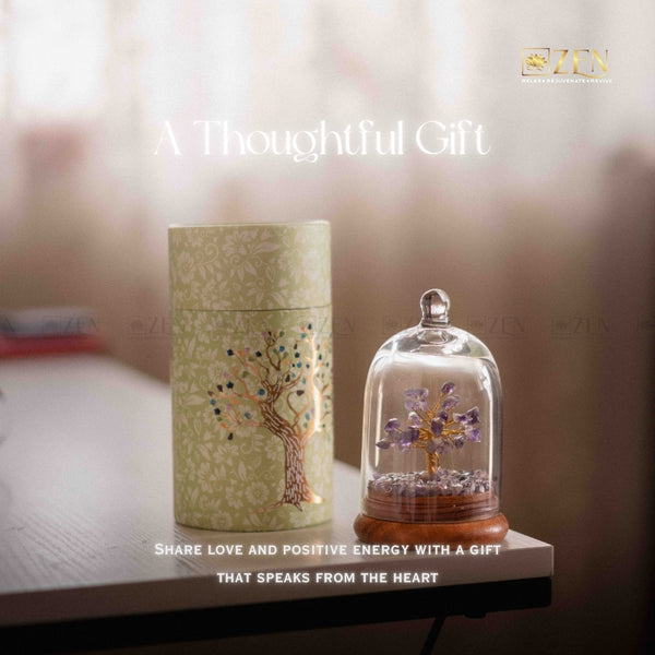 Decorative gift set with a cylindrical box and a glass dome containing a tree sculpture on a blurred background.