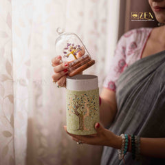 Person holding a decorative tumbler with a small tree model inside a glass dome, brand 'ZEN' visible.