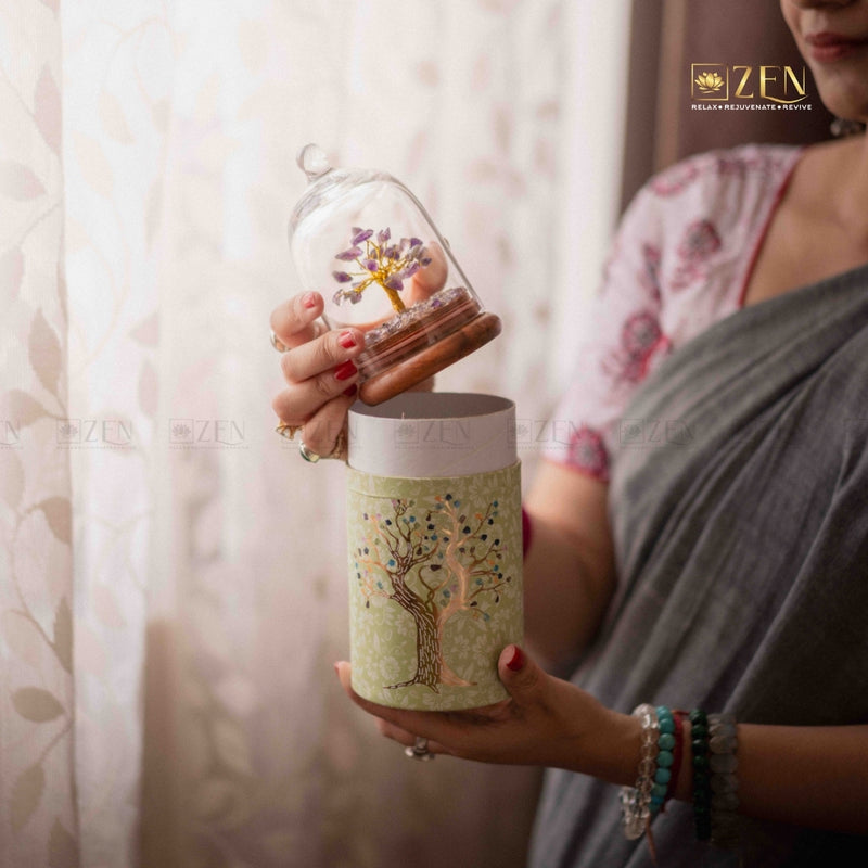 Person holding a decorative tumbler with a small tree model inside a glass dome, brand 'ZEN' visible.