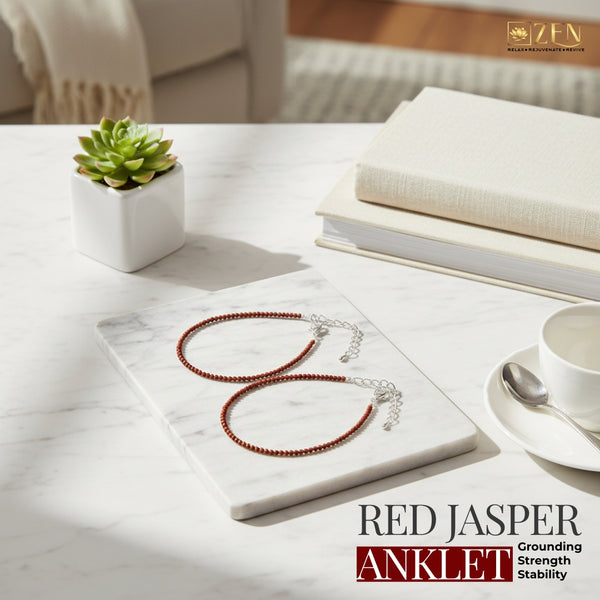 Red jasper anklet on a marble surface with books and a plant in the background