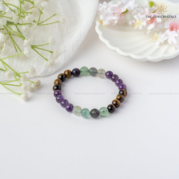 improved concentration energy bracelet on a white surface with flowers in the background, branded 'The Zen Crystals'.
