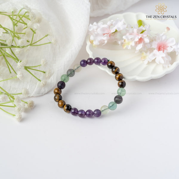 improved concentration energy  bracelet on a white surface with flowers and shells in the background, branded 'The Zen Crystals'.