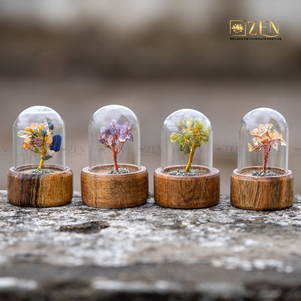 Four small trees in glass domes on wooden bases with a blurred background.