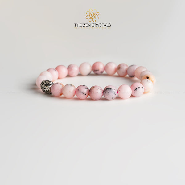 Pink opal bracelet with a silver charm on a light gray background, branded 'The Zen Crystals'.