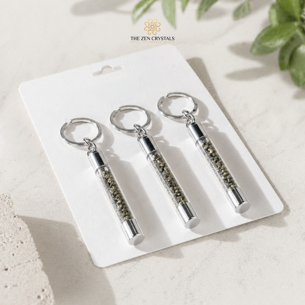 Three PYRITE SLIM TUBE keychains on a white card with 'The Zen Crystals' branding, placed on a light surface with greenery.