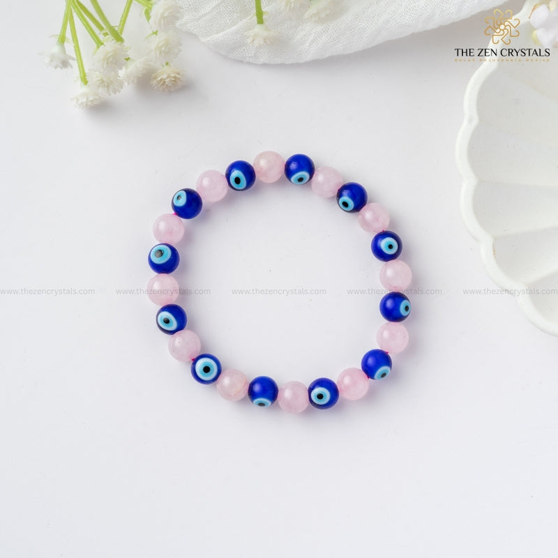 Love & Protection Energy Bracelet with pink and blue beads on a white surface with flowers in the background