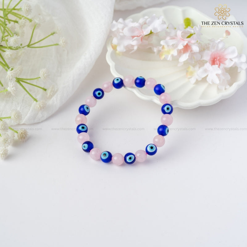 Love & Protection Energy Bracelet with blue and pink beads on a white background with flowers and shells.