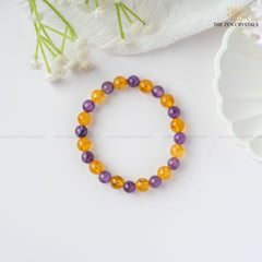 Success Alignment Energy Bracelet with purple and orange beads on a white surface with flowers.
