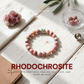Rhodochrosite bracelet on a wooden surface with crystals and leaves, featuring Puizen Crystals branding.