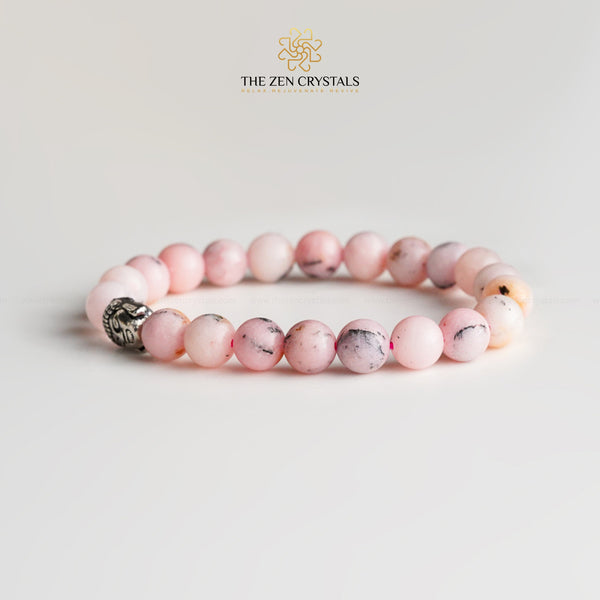 Pink opal bracelet with a silver charm on a light gray background, branded 'The Zen Crystals'.