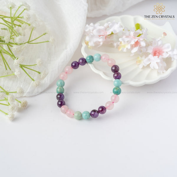 Relaxation Energy Bracelet on a white surface with flowers and a shell, branded 'The Zen Crystals'.