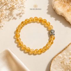 citrine bracelet with Buddha charm on a beige fabric background, featuring 'The Zen Crystals' brand.