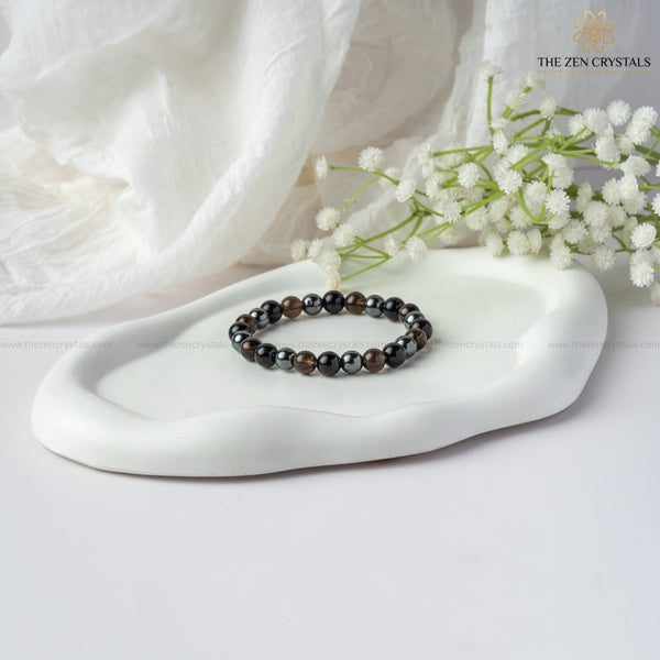 Safe Travel Energy Bracelet on a white dish with white flowers and 'The Zen Crystals' branding.