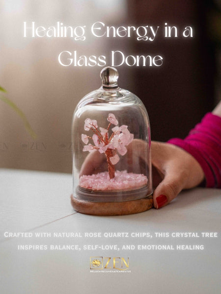 Glass dome with a crystal tree inside, held by a hand, on a light surface.