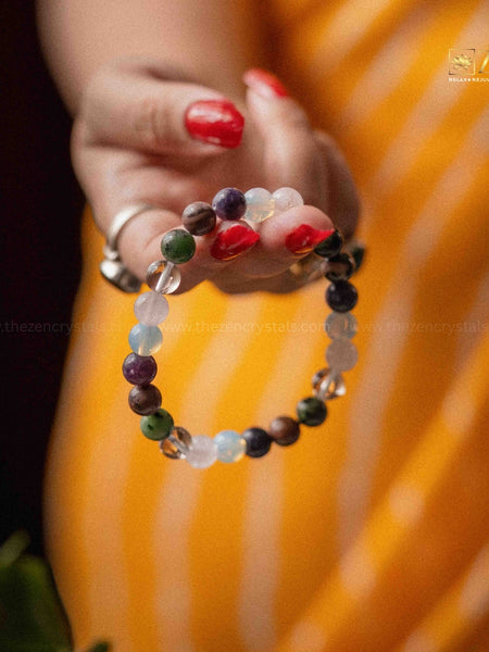 Close-up of a hand wearing a colorful beaded bracelet with a blurred orange background