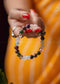 Close-up of a hand wearing a colorful beaded bracelet with a blurred orange background