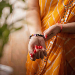 Person wearing a yellow saree with red nail polish and a ruling number 8 bracelets on a blurred background