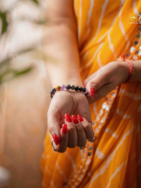 Person wearing a yellow saree with red nail polish and a ruling number 8 bracelets on a blurred background