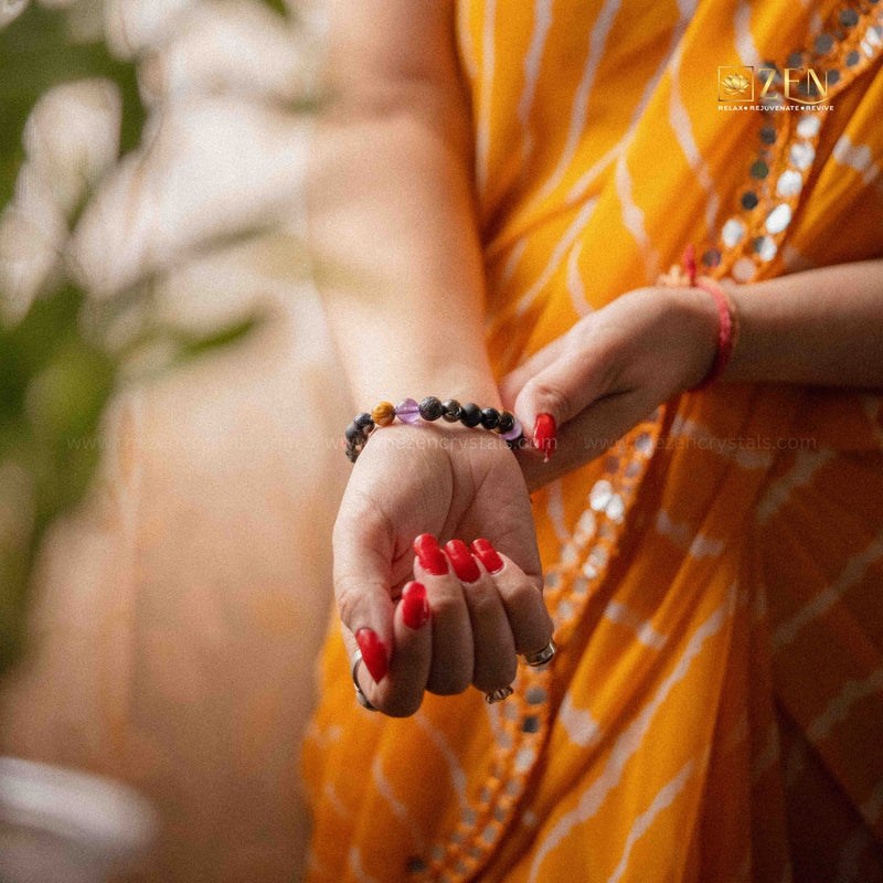 Person wearing a yellow saree with red nail polish and a ruling number 8 bracelets on a blurred background