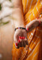 Person wearing a yellow saree with red nail polish and a ruling number 8 bracelets on a blurred background