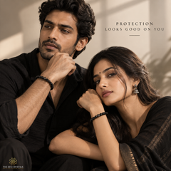 A man and a woman in black clothing wearing black obsidian bracelets, posed in a warm, sunlit indoor setting with the text 'PROTECTION LOOKS GOOD ON YOU' and 'THE ZEN CRYSTALS' logo.