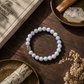 blue lace agate bracelet on a wooden surface with crystals and a book in the background
