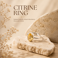A silver-tone ring with a round yellow citrine gemstone, displayed on textured beige stone props with decorative dried flowers. The image features text overlays reading 'CITRINE RING' and 'Radiate Positivity.