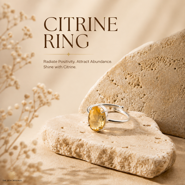 A silver-tone ring with a round yellow citrine gemstone, displayed on textured beige stone props with decorative dried flowers. The image features text overlays reading 'CITRINE RING' and 'Radiate Positivity.