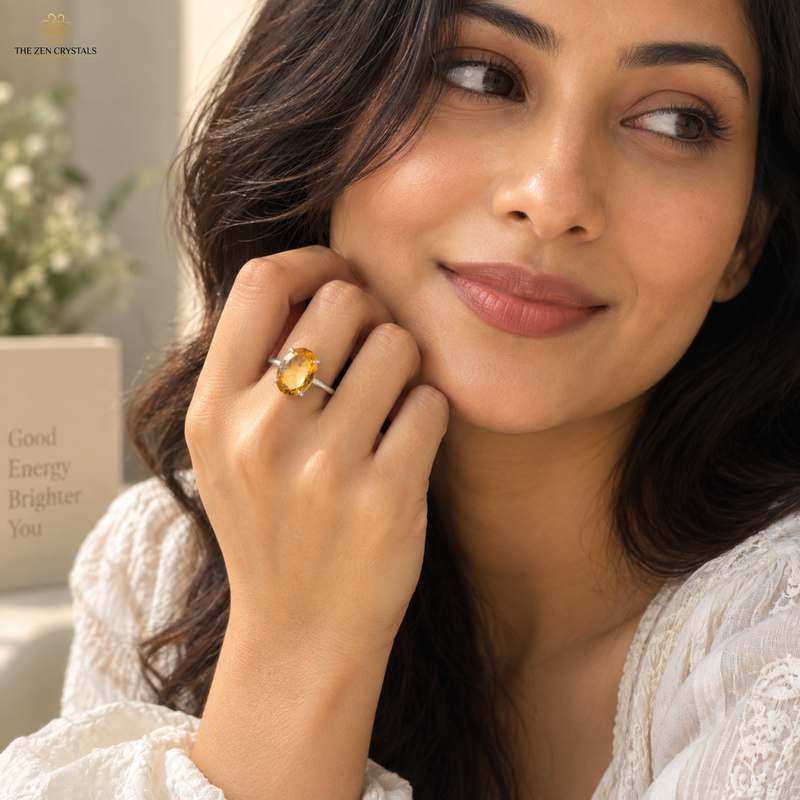 A woman wearing a silver ring with a large oval yellow gemstone, shown in a close-up lifestyle shot. The brand logo 'THE ZEN CRYSTALS' is visible in the top left corner.