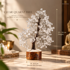 A decorative crystal tree centerpiece made of clear quartz stones on a dark brown wooden base, shown on a tabletop in a warm indoor setting with text indicating height 23-24 cm and base diameter 8-8.5 cm.