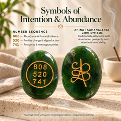 Two polished green jadeite-style oval stones displayed on a stone surface with decorative props. The left stone is engraved with the number sequence 808, 520, 741 in gold.