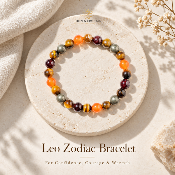 A beaded stretch bracelet displayed on a round stone slab, with decorative fabric and dried flowers around it. The bracelet features a mix of orange, brown, gray, and deep burgundy beads.