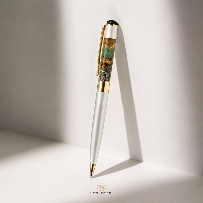A luxury Money magnet ballpoint pen with a silver-finished barrel, gold accents, and a detailed green and gold inlay on the cap, standing upright on a white surface with dramatic side lighting.