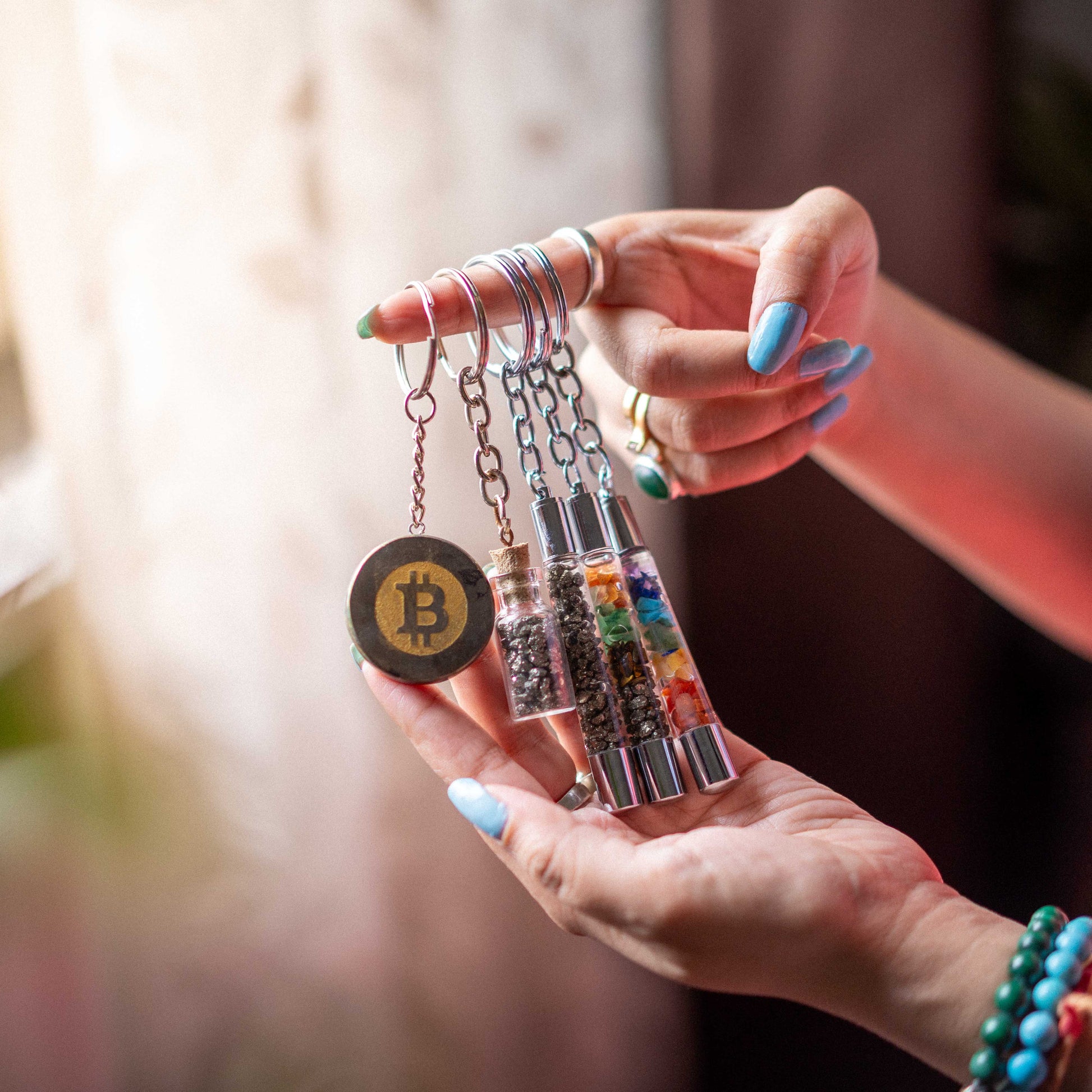 Hand holding a collection of keychains with a Bitcoin coin charm.