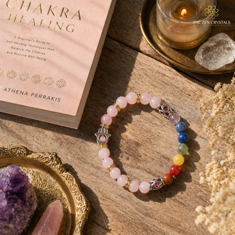 Chakra healing bracelet on a wooden surface with a book and crystals.