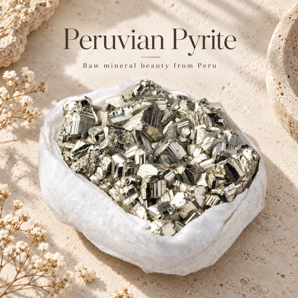 A white fabric pouch filled with shiny metallic peruvian pyrite crystals, styled on a light beige stone surface with dried flowers and decorative stones. Text at the top reads 'Peruvian Pyrite' and 'Raw mineral beauty from Peru'.