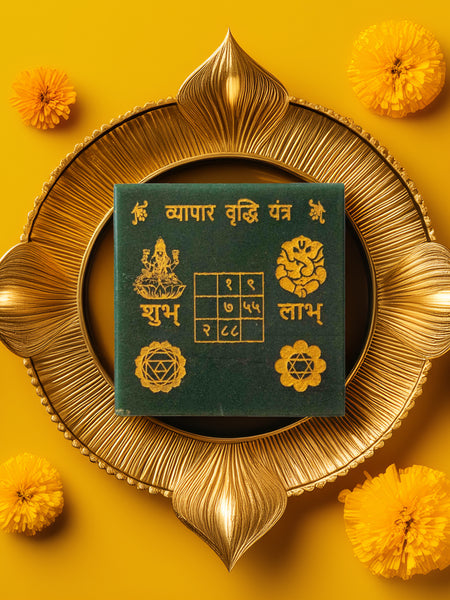 Green jade vyapar vridhi yantra on a decorative yellow background with flowers and candles.