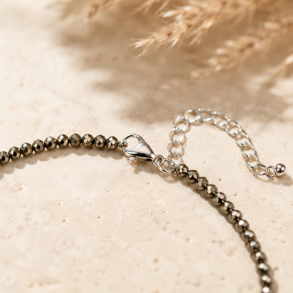 close up of pyrite anklet on a textured beige surface